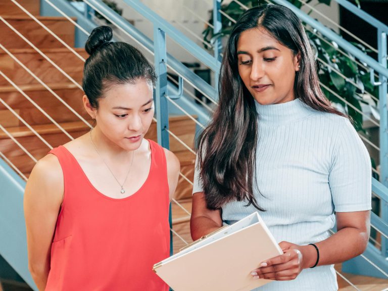 Two women engaged in teamwork, discussing documents in a stylish office setting.
